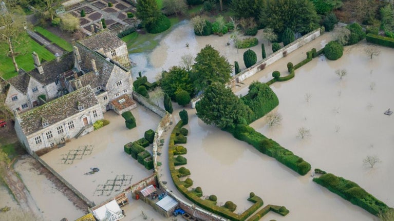 An aerial photo showing parts of Avebury Manor and the surrounding gardens underwater.